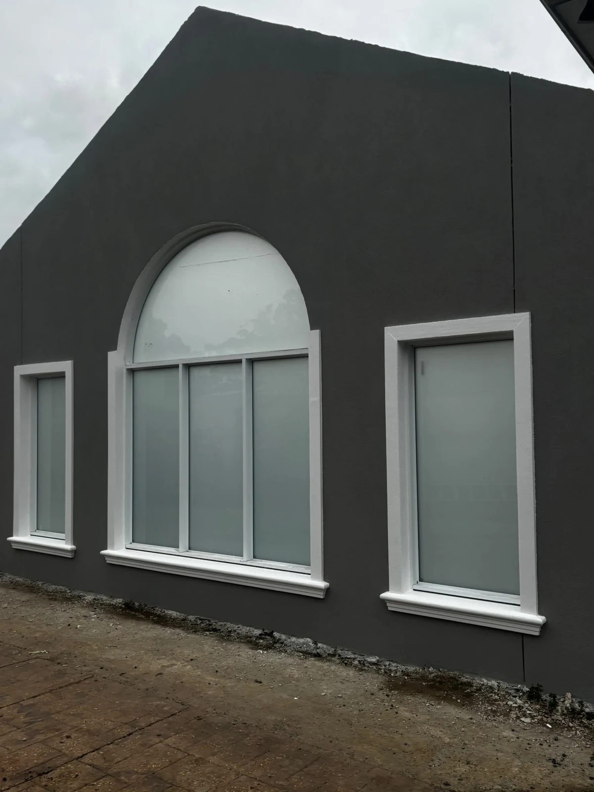 Charcoal exterior wall with a light arched window surround