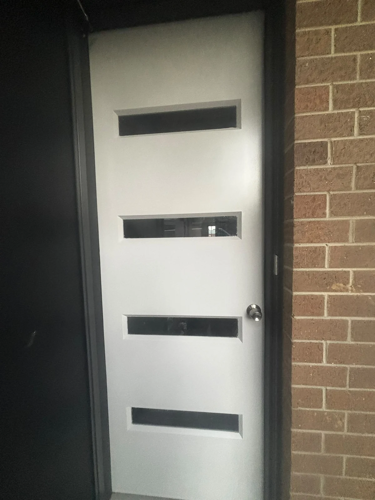 White entrance door with three dark horizontal glass panels
