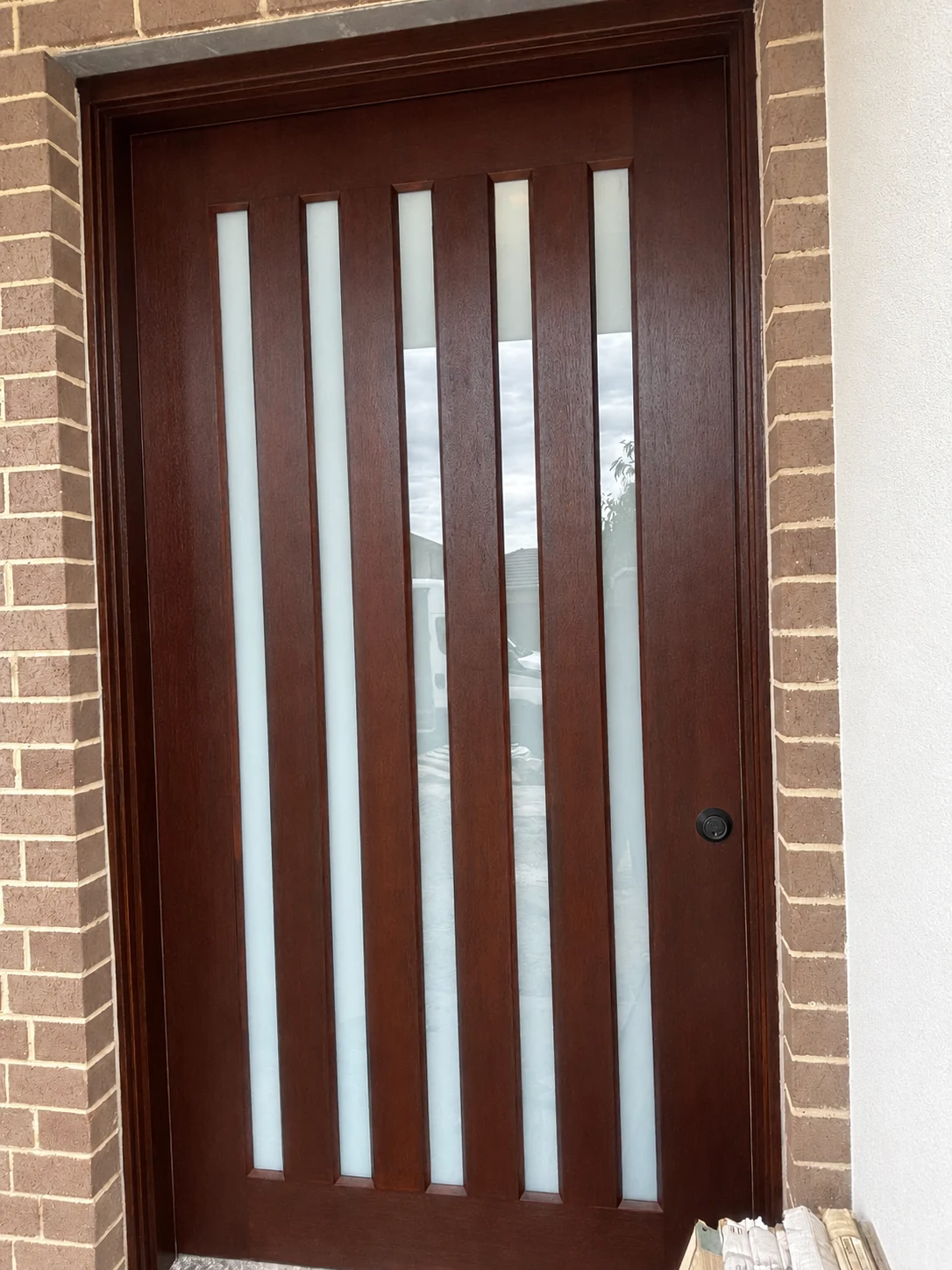 Dark timber entrance door with five vertical glass panels