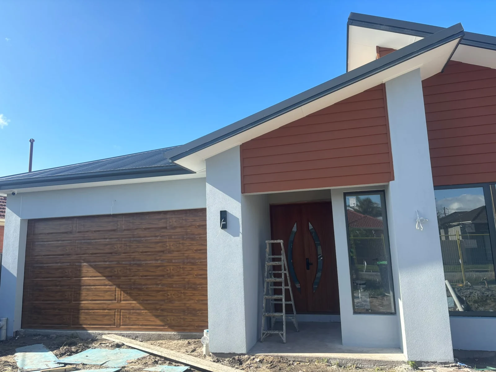 House facade with white columns and warm cladding, with work materials visible
