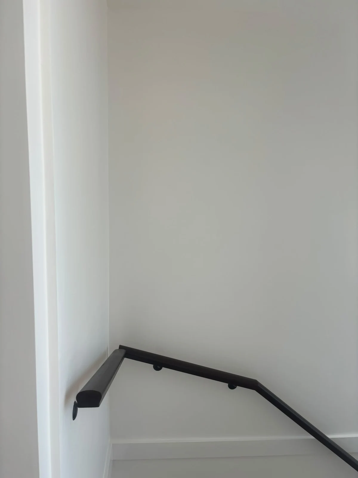 Light stairwell wall with a dark handrail